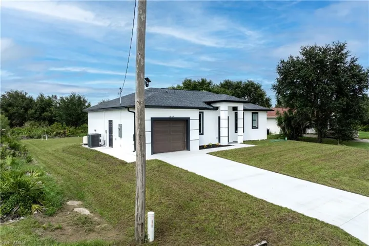 View of front of property with stucco siding, a garage, a front yard, and driveway