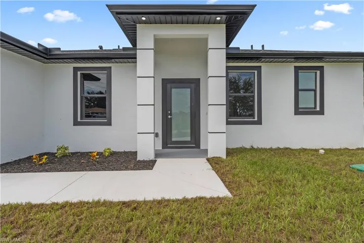 Doorway to property featuring stucco siding and a lawn