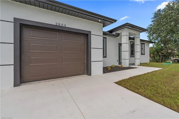 View of front of home with stucco siding, concrete driveway, and a front lawn