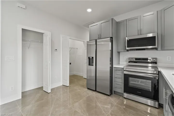 Kitchen with appliances with stainless steel finishes, gray cabinets, and recessed lighting
