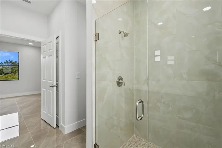 Full bath featuring a marble finish shower, recessed lighting, and light tile patterned floors
