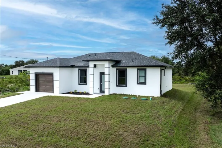 Prairie-style home with concrete driveway, roof with shingles, an attached garage, and a front yard