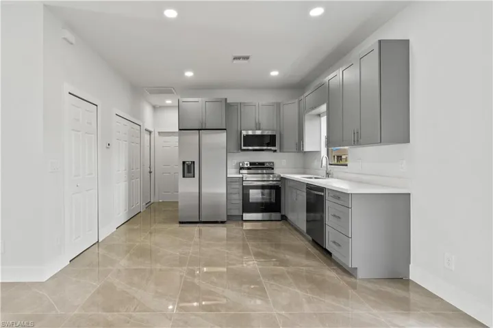 Kitchen with light countertops, appliances with stainless steel finishes, gray cabinets, and recessed lighting