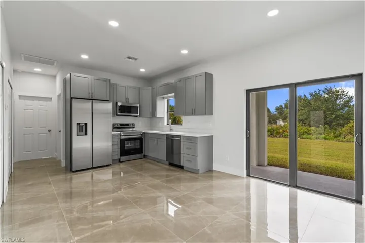 Kitchen with gray cabinets, stainless steel appliances, light countertops, recessed lighting, and light marble finish flooring