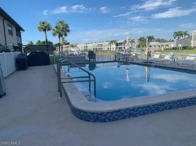 Community pool with a patio area and a grill