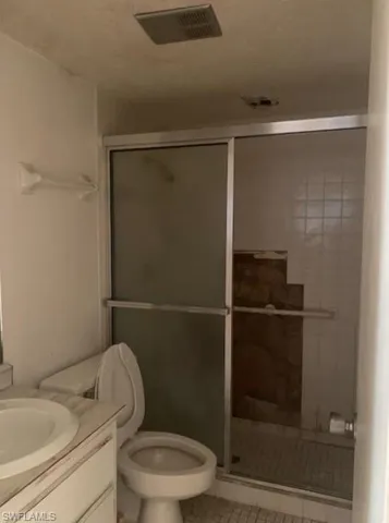 Full bath featuring vanity, a stall shower, tile patterned floors, and a textured ceiling