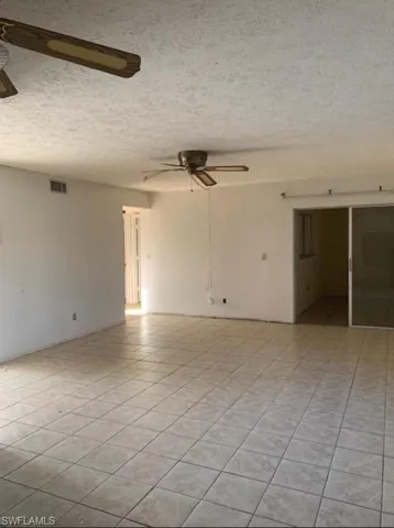 Unfurnished room featuring ceiling fan, a textured ceiling, and light tile patterned floors