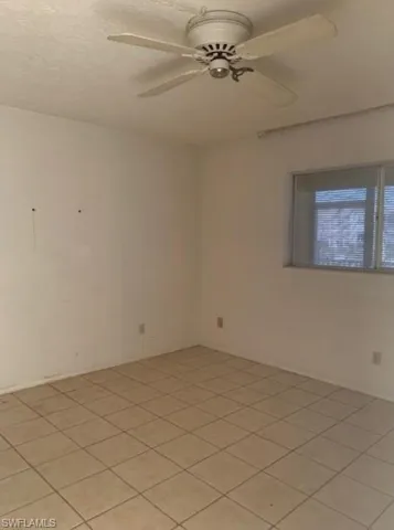 Spare room featuring ceiling fan, light tile patterned floors, and a textured ceiling