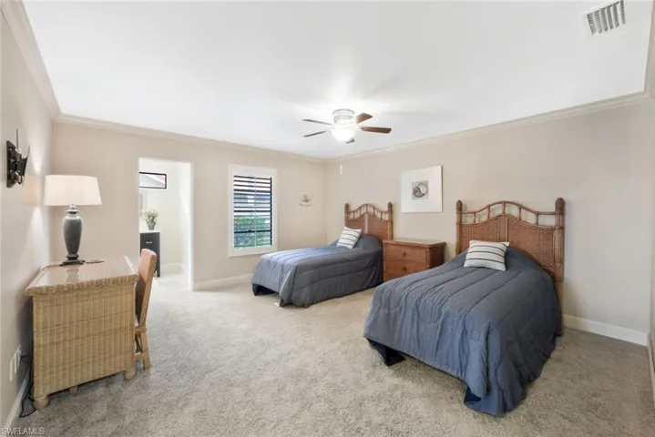Carpeted bedroom featuring ceiling fan and crown molding