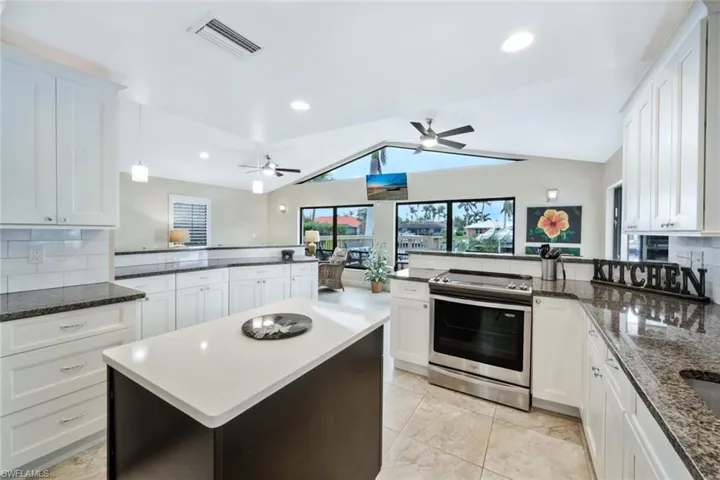 Kitchen featuring lofted ceiling, electric stove, kitchen peninsula, and tasteful backsplash