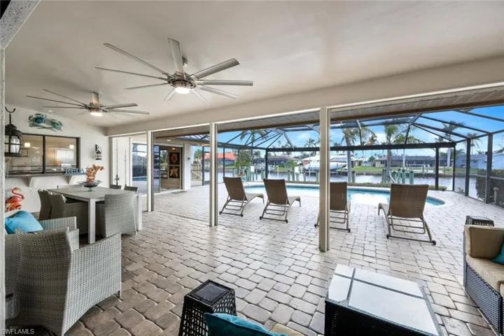 View of patio / terrace featuring glass enclosure, ceiling fan, a water view, and an outdoor living space