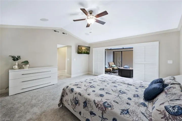 Carpeted bedroom with ceiling fan, crown molding, and lofted ceiling