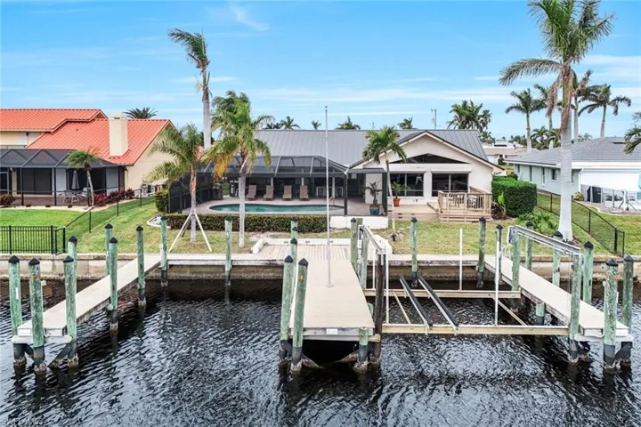 Dock area with a patio, a lanai, a water view, a yard, and a fenced in pool