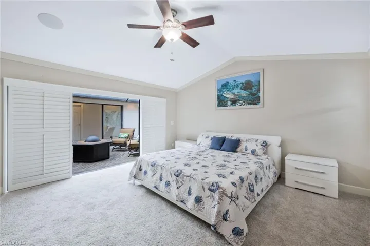 Carpeted bedroom with ceiling fan and lofted ceiling