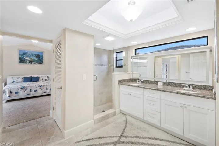 Bathroom with a tray ceiling, crown molding, vanity, and a shower with shower door