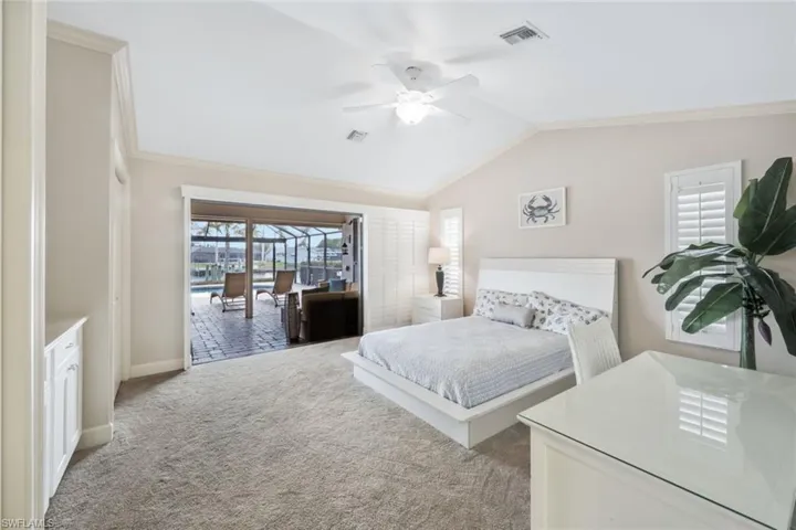 Carpeted bedroom featuring access to outside, vaulted ceiling, ceiling fan, and ornamental molding
