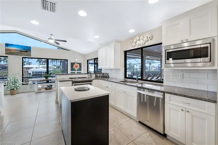Kitchen featuring sink, backsplash, vaulted ceiling, white cabinets, and appliances with stainless steel finishes