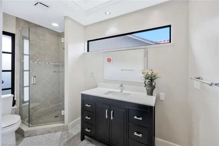 Bathroom with vanity, toilet, walk in shower, and ornamental molding
