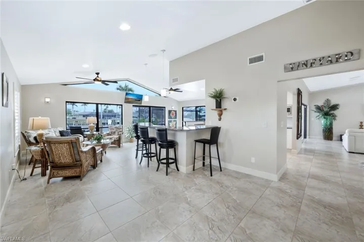 Kitchen with a kitchen breakfast bar, ceiling fan, a wealth of natural light, and vaulted ceiling