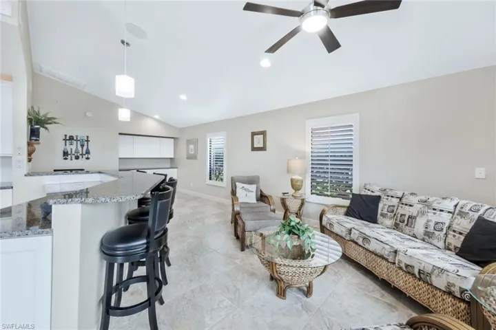 Living room with ceiling fan and lofted ceiling