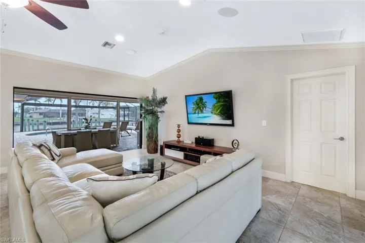 Living room with ceiling fan, lofted ceiling, and ornamental molding