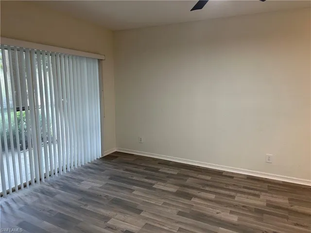 Empty room with dark wood-type flooring and ceiling fan