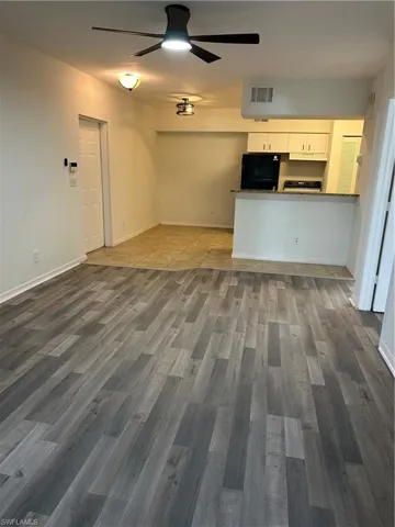 Kitchen with hardwood / wood-style floors, white cabinetry, fridge, ceiling fan, and exhaust hood