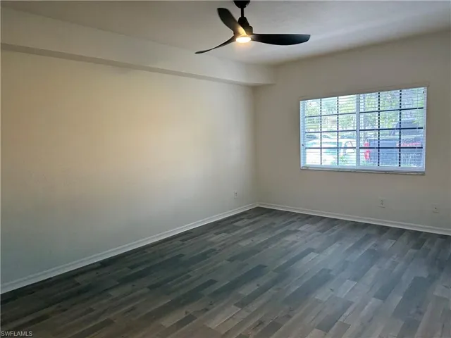 Unfurnished room featuring dark wood-type flooring and ceiling fan