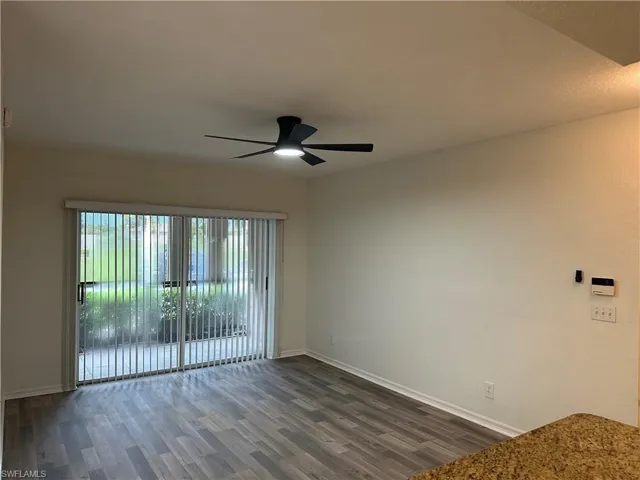 Empty room with ceiling fan and dark hardwood / wood-style floors