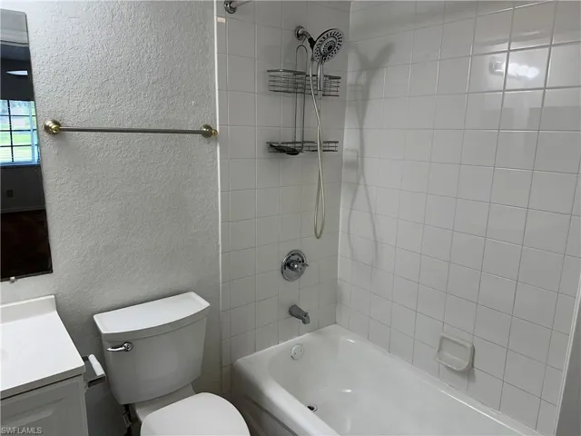 Full bathroom with tiled shower / bath combo, vanity, and toilet