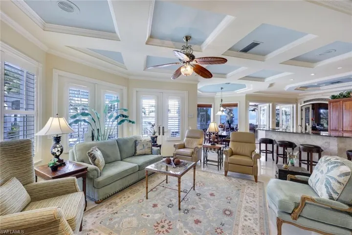 Living room featuring french doors, coffered ceiling, ceiling fan, crown molding, and beam ceiling