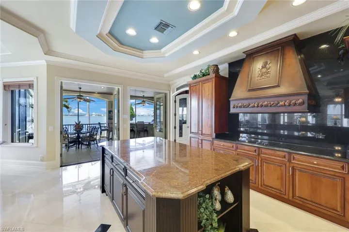 Kitchen featuring black cooktop, a kitchen island, dark stone counters, and crown molding