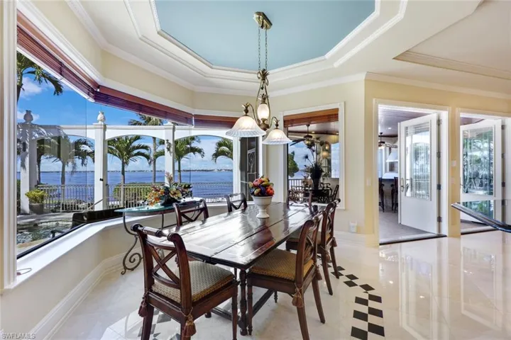 Dining room featuring a water view, a raised ceiling, and crown molding only steps to your private beach.