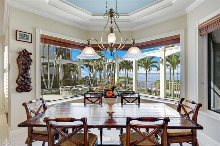 Dining space featuring a tray ceiling, a water view, and ornamental molding