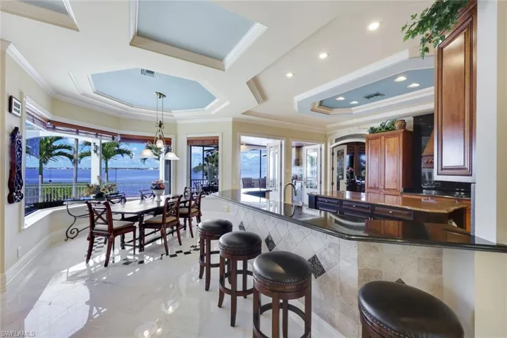 Kitchen with a kitchen bar, kitchen peninsula, ornamental molding, a tray ceiling, and hanging light fixtures