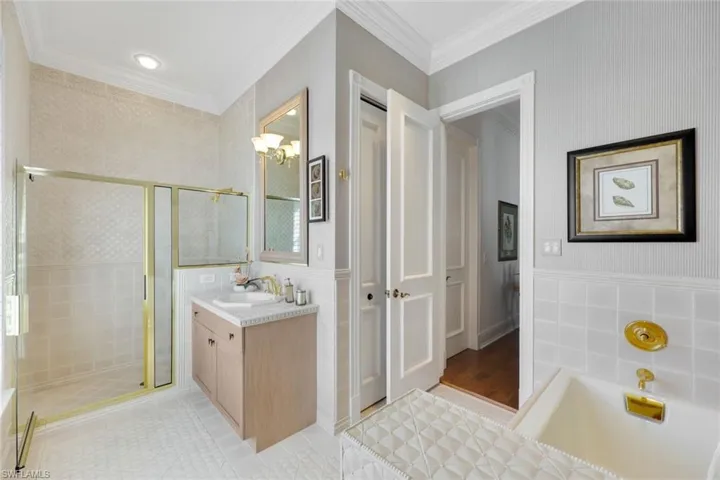 1 floor ensuite bathroom to the 1st of 2 first floor bedroom suites. Bathroom with vanity, plus walk in shower, ornamental molding, tile walls.
