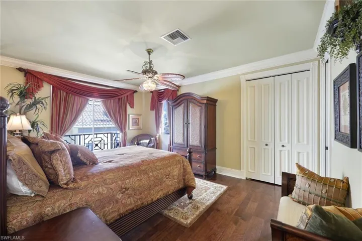 3 bedroom located on the 2nd floor with private bathroom ensuite and private balcony with water views, Bedroom featuring ceiling fan, dark hardwood / wood-style flooring, and ornamental molding.