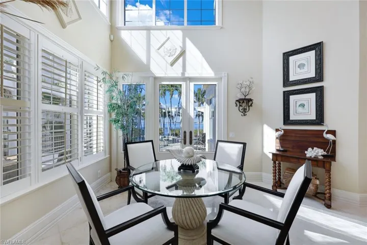 Dining room with light tile patterned floors, a towering ceiling, and plenty of natural light