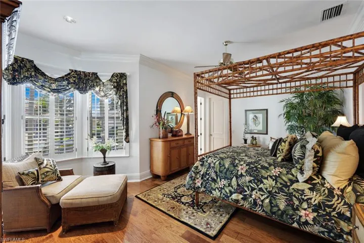 1st of the 2 first floor Bedrooms with crown molding and hardwood / wood-style flooring and furnished with Tommy Bahama Furnishings supporting it's large closet and ensuite bathroom.
