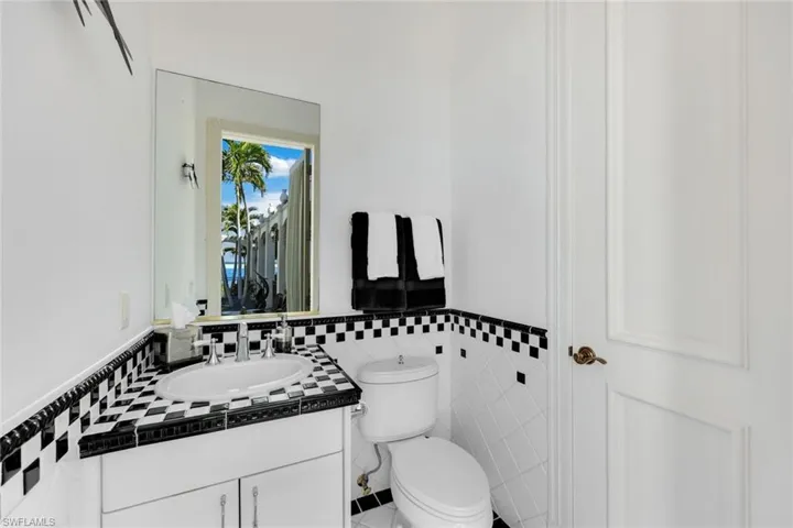 Pool 1/2 Bathroom featuring tile patterned flooring, vanity, toilet, and tile walls and a 2nd 40 gallon hot water heater in the closet with pool storage.