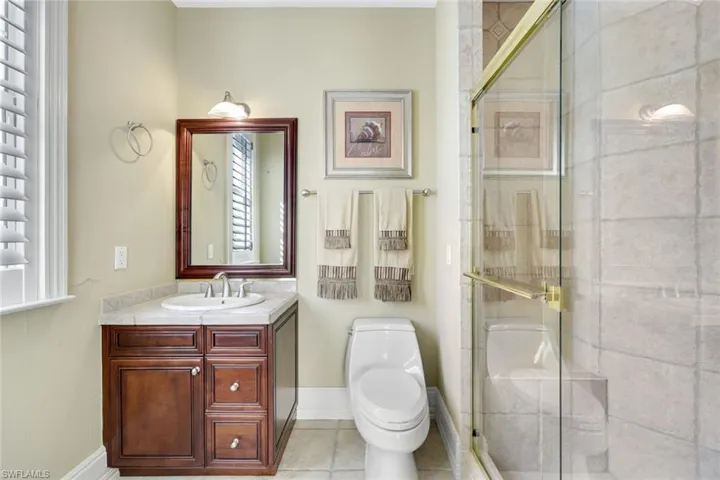 Bathroom featuring tile patterned floors, vanity, toilet, and a shower.