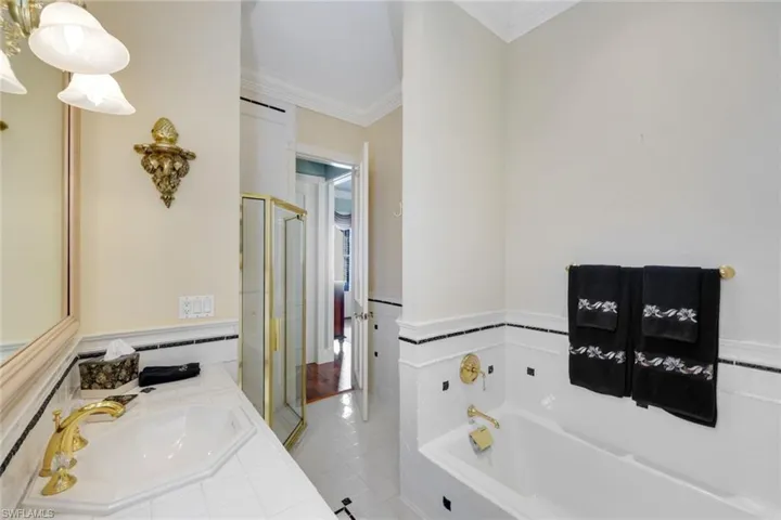 Ensuite Bathroom with tile patterned flooring, vanity, shower with separate bathtub, and crown molding.