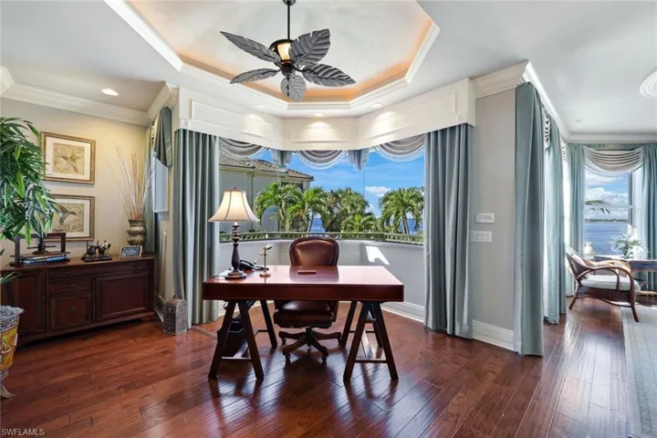 In the owners suite you'll find Office space and a separate sitting area with a balcony over looking the lagoon style pool, spa and private beach with a tray ceiling, ceiling fan, and dark hardwood / wood-style floors.