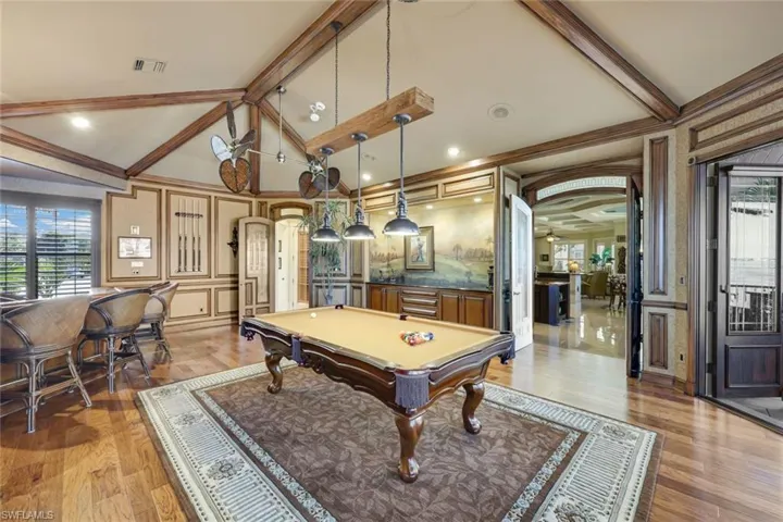 The wall in the distance is a painting of a famous Golfer, Bobby Jones, a hand made painting surrounding him on the wall to complete the stunning visual.  2 sets of french doors leading into the kitchen and outside bar with Cherry Wood ceiling and Alfresco Grille, 2 Alfresco side burners, wet bar, granite countertops, Hurricane shutters, Clear vinyl motorized curtains.