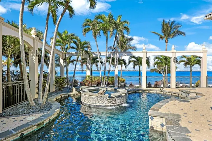 View of swimming pool with pool water feature, a water view, and an in ground hot tub