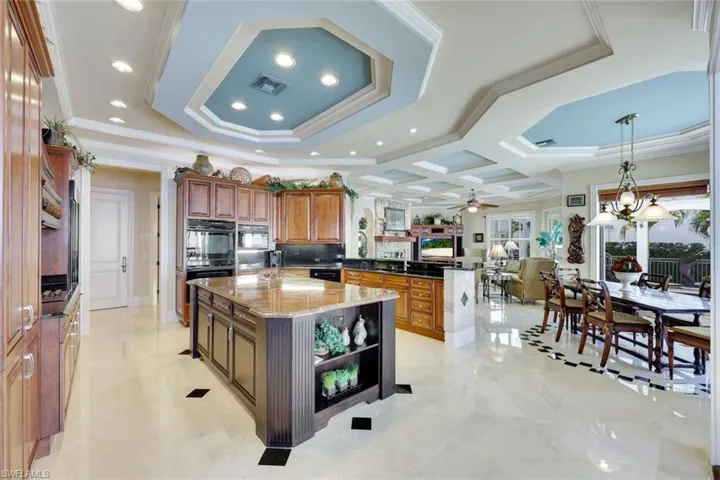 Kitchen with pendant lighting, a center island, ceiling fan with notable chandelier, dark stone countertops, and ornamental molding