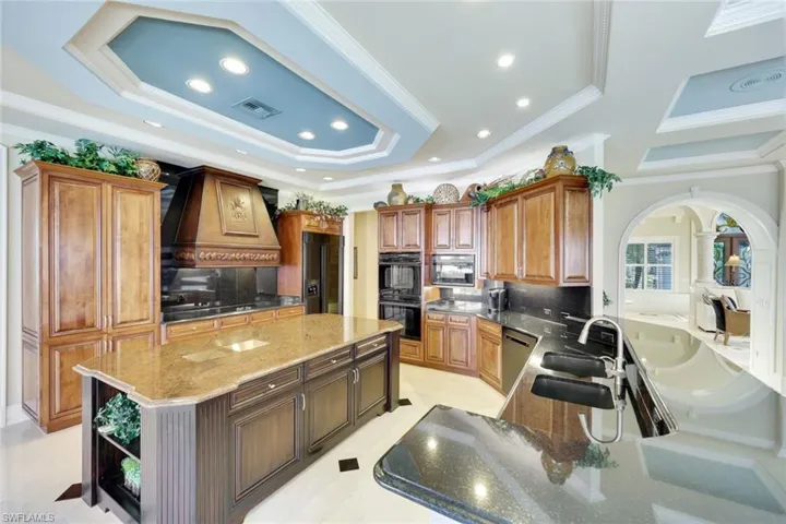 Kitchen with tasteful backsplash, premium range hood, crown molding, black appliances, and a kitchen island