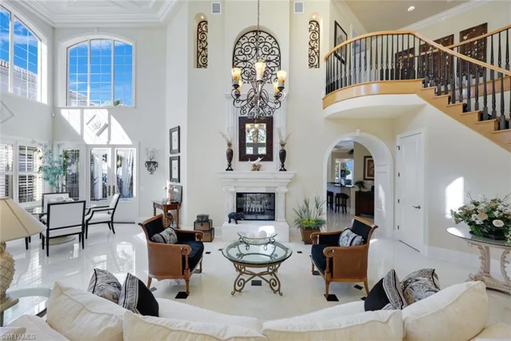 Living room with marble Floors, Marble posts, a towering ceiling approx. 25 ft, ornamental molding, and an inviting chandelier.  French doors to the pool and private beach, double sided fireplace marble and stone fireplace that has never been used