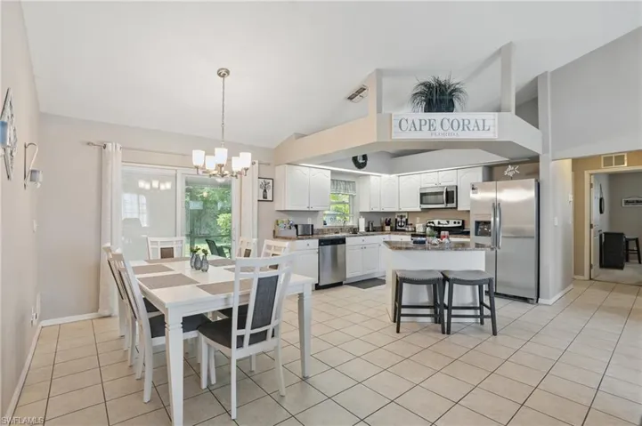 Dining space featuring vaulted ceiling, a chandelier, light tile patterned floors, and baseboards