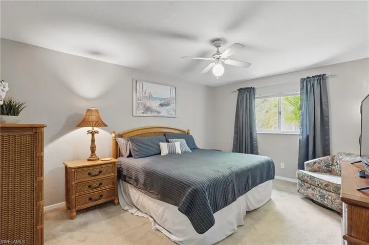 Bedroom with light colored carpet, baseboards, and ceiling fan